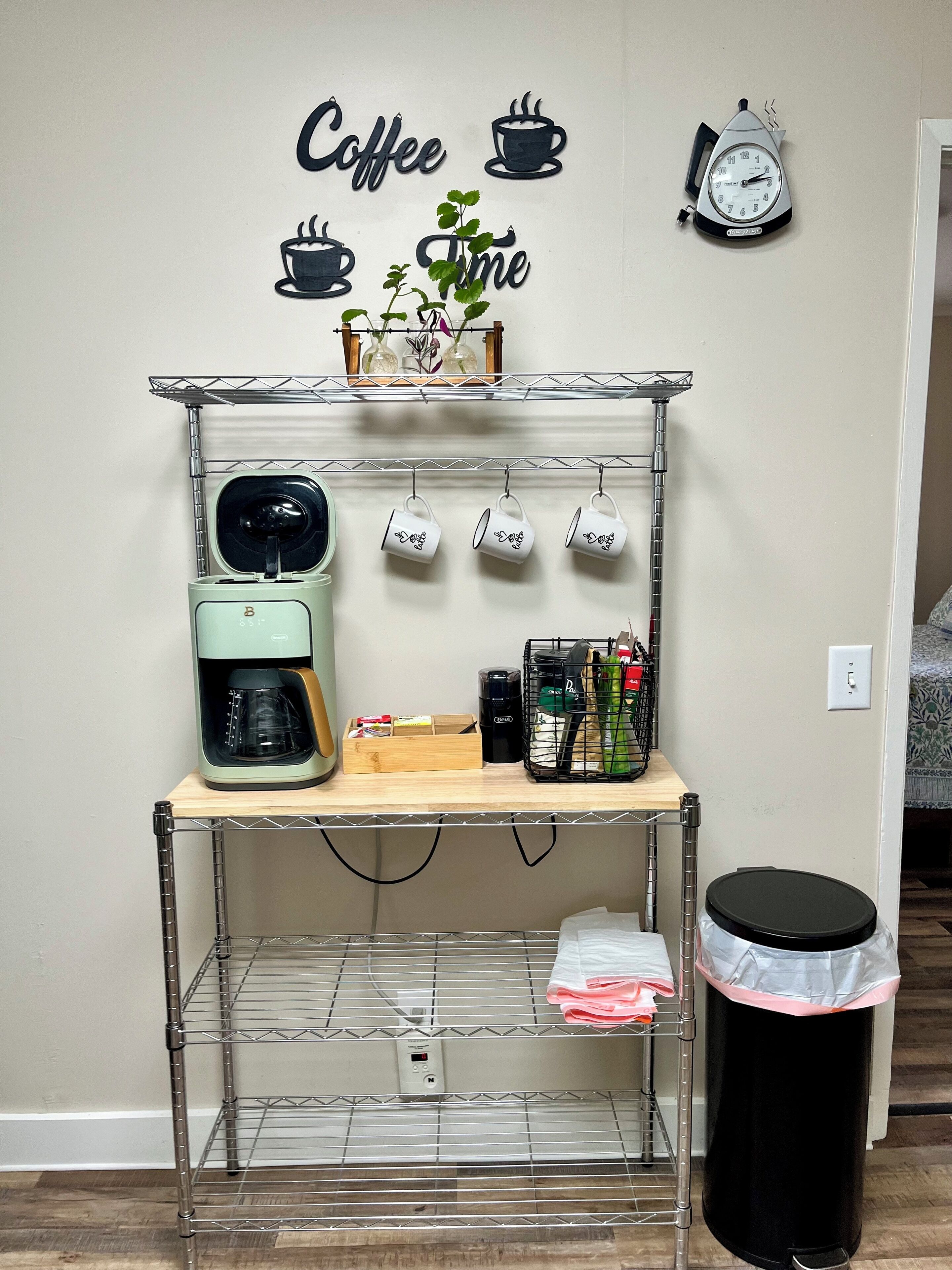 Un coin café équipé d’une machine à café, de tasses et d’une horloge murale.