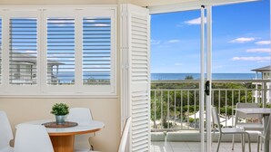 A balcony with a view of the ocean, white furniture, and a small table with a plant. - The Pool Resort - One Bedroom Pool & Ocean Views (Tweed)