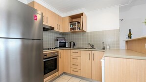 A modern kitchen with stainless steel appliances, wooden cabinets, and a tiled backsplash. - The Pool Resort - One Bedroom Pool & Ocean Views (Tweed)