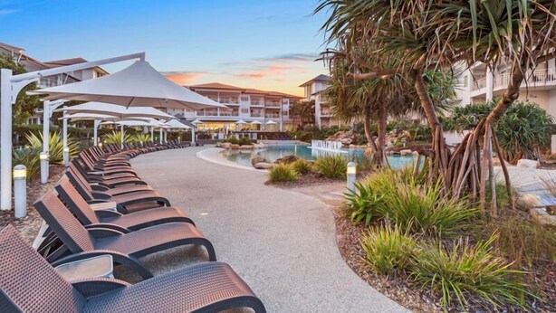 A resort with a pool, lounge chairs, and a covered walkway. - The Pool Resort - 1BR Pool View Haven (KINGSCLIFF)