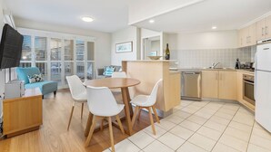 A modern apartment with a dining area, kitchen, and living space. - The Pool Resort - 1BR Pool View Haven (KINGSCLIFF)