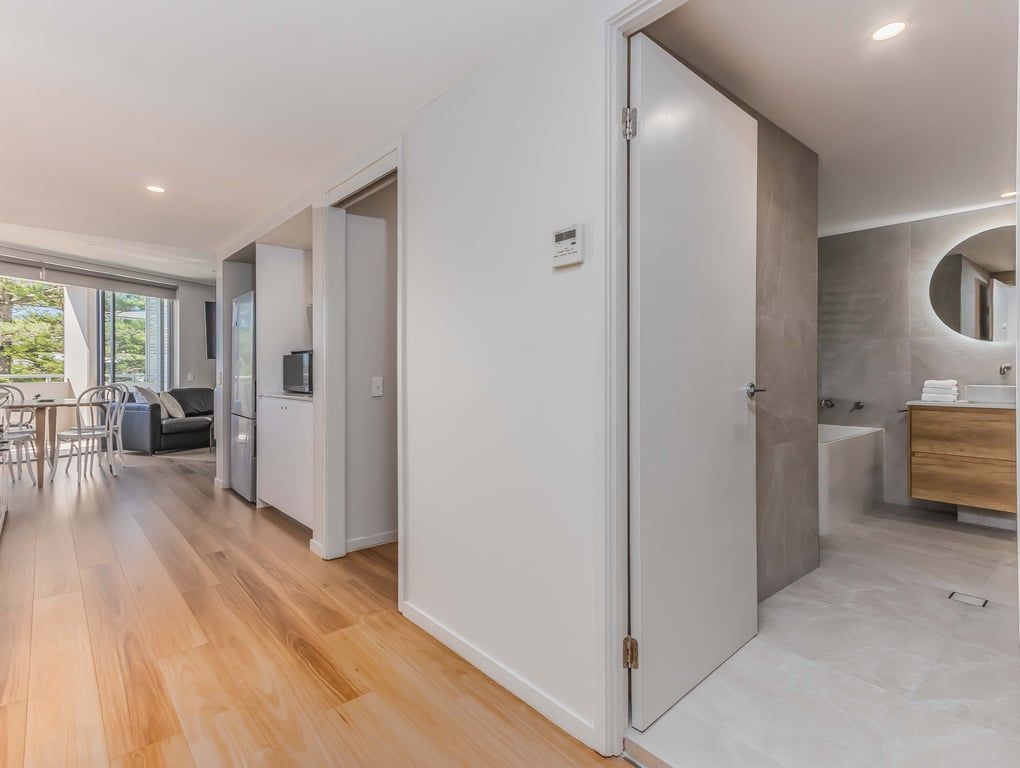 A modern interior with a wooden floor, a dining area, a kitchen, and a bathroom with a bathtub.