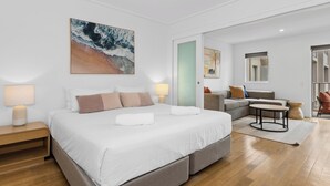 A modern hotel room with a large bed, a sofa, a small table, and a painting on the wall. - The Sand Resort Kingscliff - One Bed Pool view (3202) (Tweed)