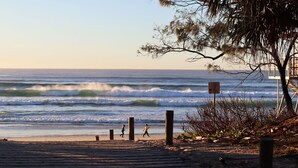 A beach with wooden walkways, a lifeguard tower, and waves crashing onto the shore. - The Sand Resort Kingscliff - One Bed Pool view (3202) (Tweed)