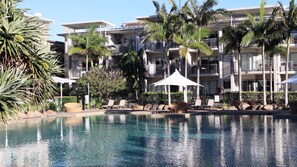 Un hôtel doté d’une piscine, de chaises longues et de palmiers.