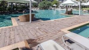 A pool area with lounge chairs and umbrellas, surrounded by a wooden deck and a pool with clear water. - The Sand Resort Kingscliff - One Bed Pool view (3302) (Tweed)