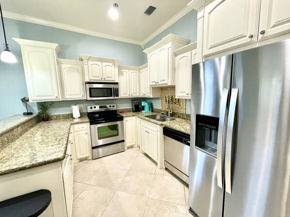 A modern kitchen with white cabinets, stainless steel appliances, and a granite countertop.