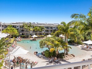 Ein Resort mit Pool, Strandbereich und einem Gebäude mit Balkonen.