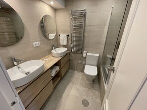 Een bad/douchecombinatie, een haardroger, handdoeken, toiletpapier