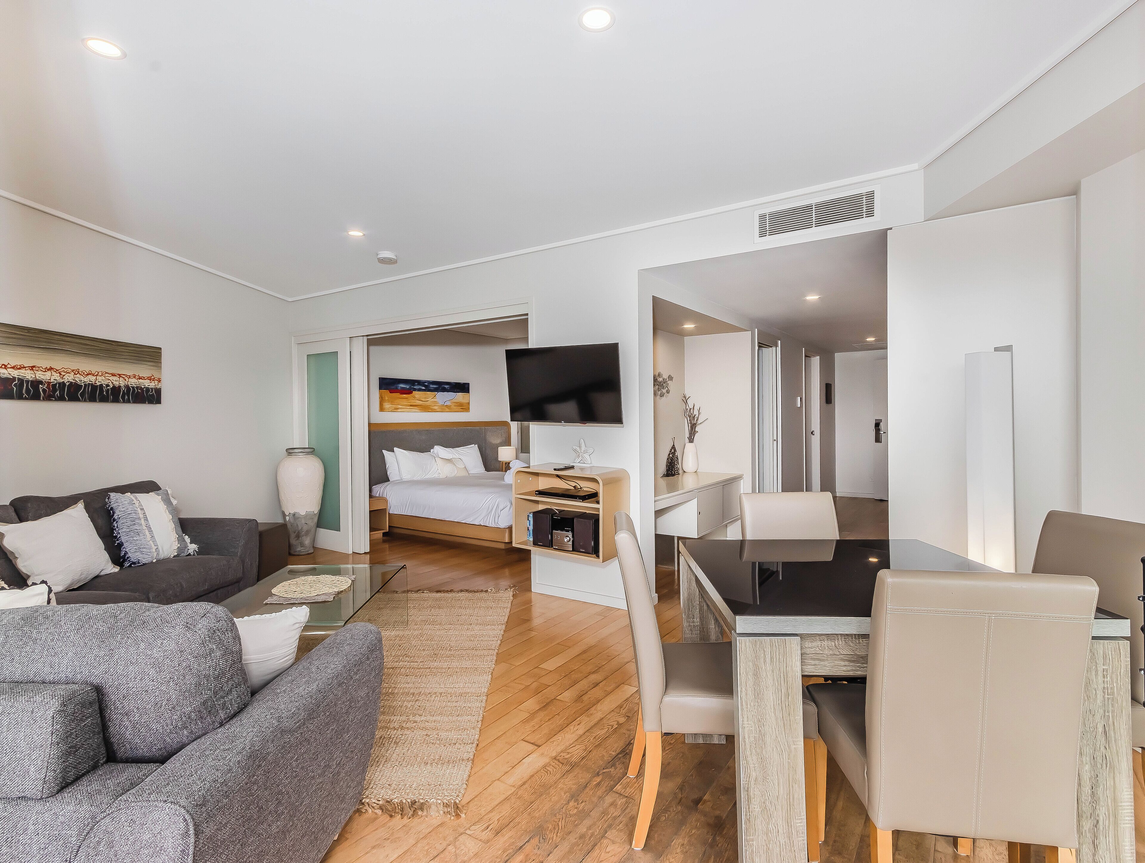 A modern hotel room with a sofa, a bed, a desk, and a TV.