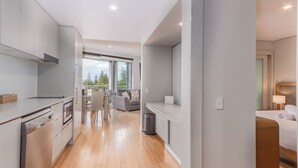 A modern kitchen with a dining area, a sofa, and a bed in a hotel room. - The Sand Resort Kingscliff -One Bed Spa Suite (4202) (Tweed)