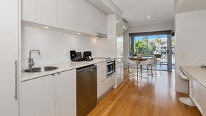 A modern kitchen with white cabinets, stainless steel appliances, and a wooden floor. - The Sand Resort Kingscliff - Dual key 2B (6217/18) (Casuarina)