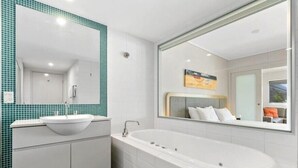 Un baño moderno con una bañera independiente, un lavamanos independiente y un espejo grande.