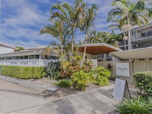 Un spa appelé « The Spa at Salt », avec une enseigne, des palmiers et un espace extérieur aménagé avec des siÚges.