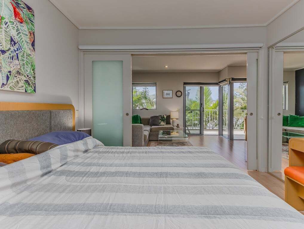 Een slaapkamer met een groot bed, een bank, een bijzettafeltje en uitzicht op het landschap door een schuifdeur.