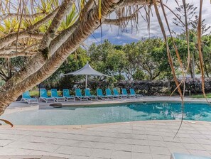 A pool area with lounge chairs and a canopy.