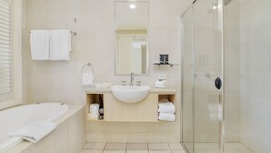 Ein modernes Badezimmer mit einer Badewanne, einem Waschbecken, einem Spiegel und einer Duschkabine.