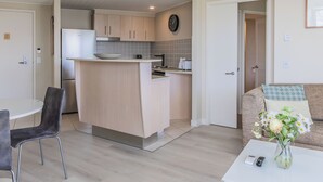 Una cocina moderna con una isla central, un comedor con una mesa redonda y sillas, y una sala de estar con un sofá y un jarrón de flores.
