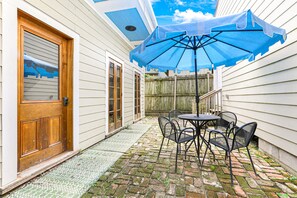 Enjoy a patio with a brick floor, patterned mat, and a wooden door with a glass panel.