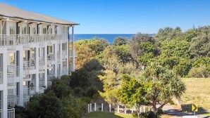 A multi-story building with balconies overlooking a coastal area.