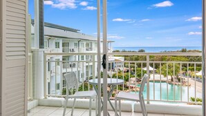 En balkon med udsigt over en swimmingpool og en bygning i baggrunden.