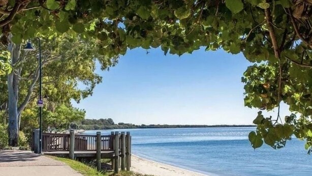 Un paseo marítimo con un banco y una cerca de madera, que conduce a una masa de agua.