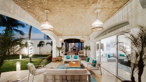 Un vaste espace de vie au design moderne, comprenant un ensemble de canapés, une table basse et un éclairage décoratif.