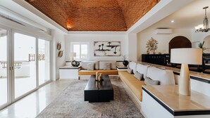 Un vaste espace de vie au design moderne, comprenant une table basse noire, un canapé beige et une grande fenêtre laissant entrer la lumière naturelle.