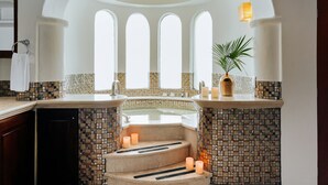 Une salle de bain avec un mur recouvert de mosaïques, une baignoire et une plante.