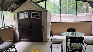 A covered patio area with a table and chairs, a ceiling fan, and a small shed. - Quiet and cozy home away from home I (Bay St. Louis)