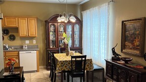 A dining area with a table set for four, a wooden cabinet, and a decorative vase. - Quiet and cozy home away from home I (Bay St. Louis)