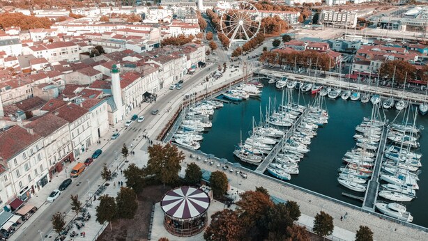 An aerial view of a harbor with boats, a Ferris wheel, and buildings. - Appartement au calme, à 15 min de la plage ! (La Rochelle)