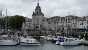 A marina with boats docked, a prominent tower in the background, and a crowd of people. - Appartement au calme, à 15 min de la plage ! (La Rochelle)