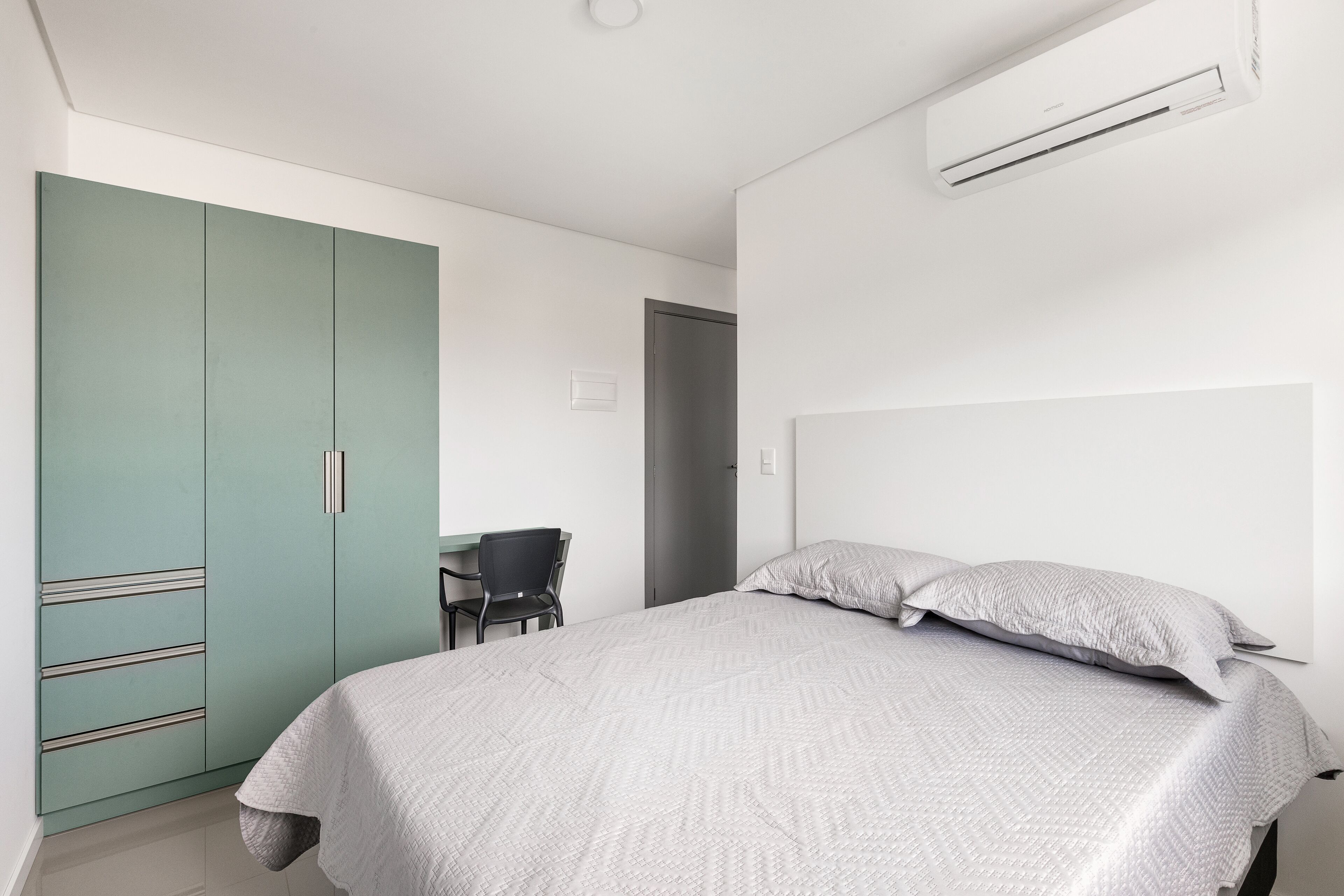 A bedroom with a bed, a desk, and a wardrobe.