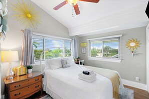 Une chambre à coucher avec un lit, une table de chevet, une lampe et un ventilateur de plafond.