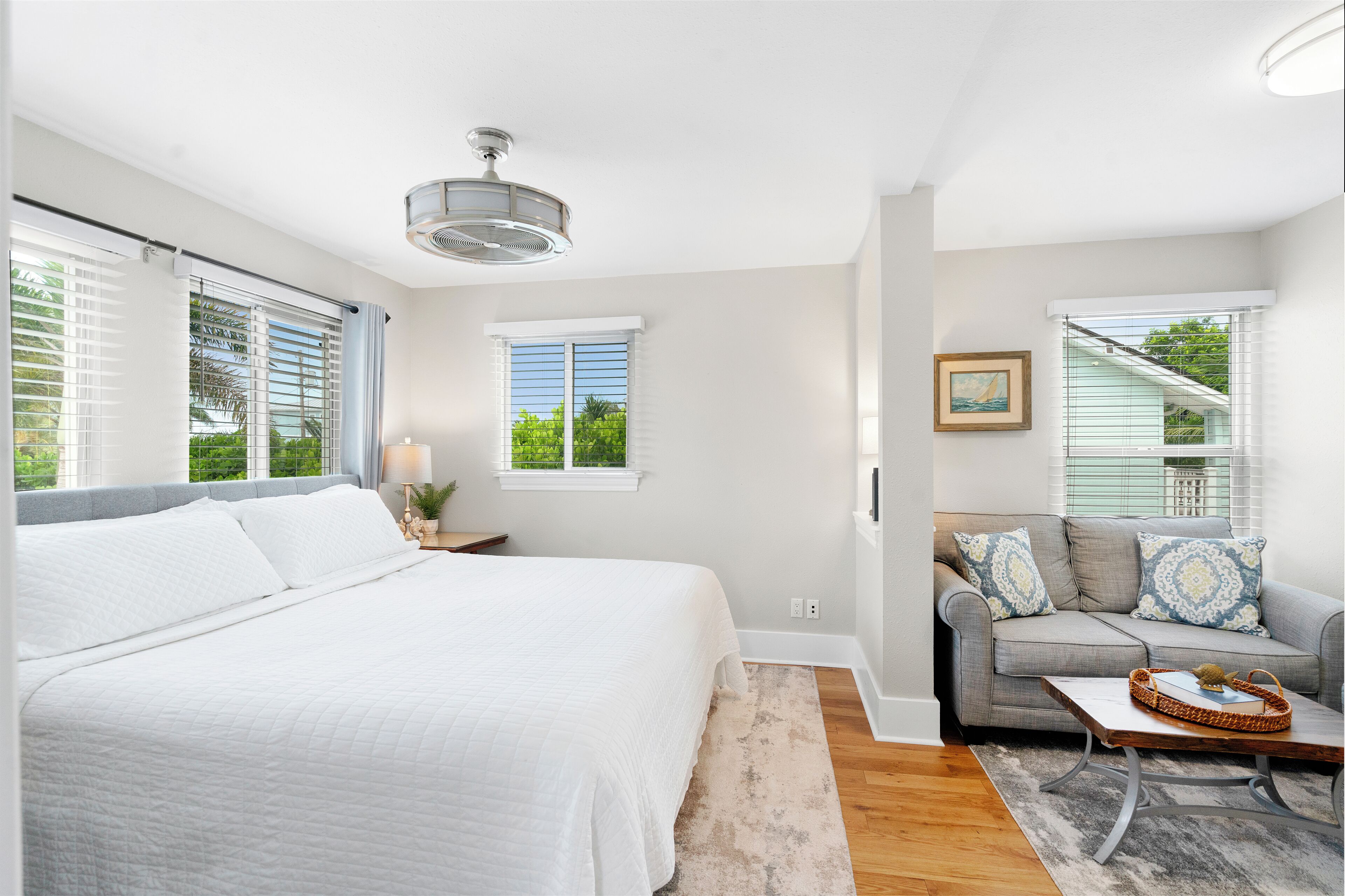 A bedroom with a large bed, a gray sofa, and a coffee table.