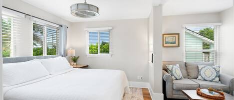 A bedroom with a large bed, a gray sofa, and a coffee table.