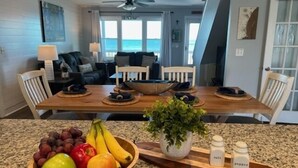 Uma área de refeições com uma mesa de madeira, cadeiras e uma tigela de frutas.