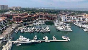 A marina with numerous boats docked, surrounded by multi-story buildings with balconies. - CONDO NAUTICO BY TRVL2HM (Puerto Vallarta)