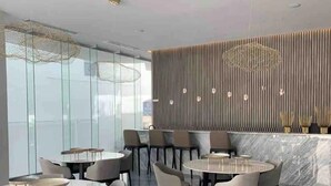 A modern dining area with round tables and chairs, a marble floor, and a decorative wall with vertical lines and hanging lights. - CONDO NAUTICO BY TRVL2HM (Puerto Vallarta)