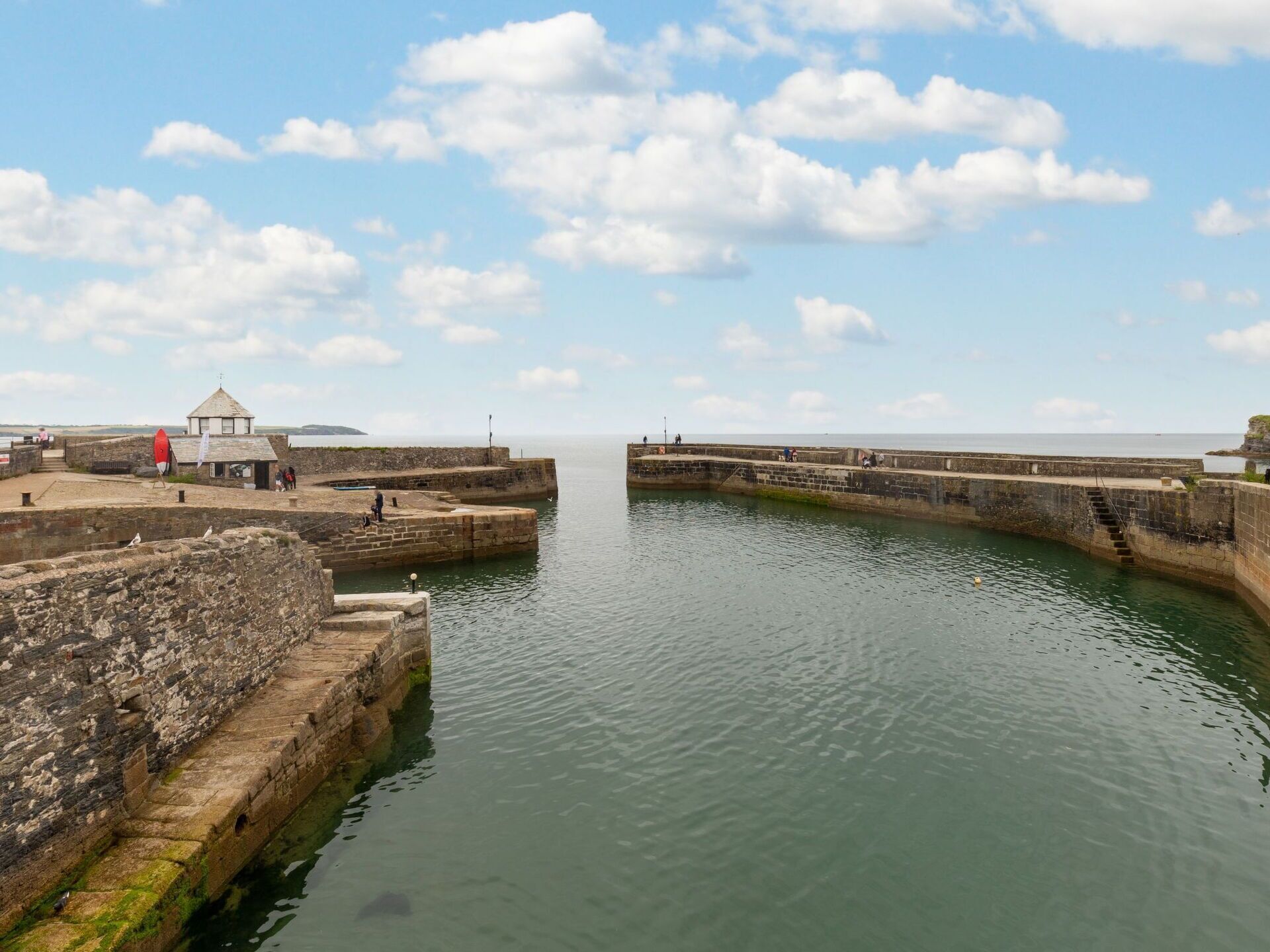 A coastal fortification with a small building, a red lifebuoy, and a clear sky.