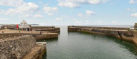 A coastal fortification with a small building, a red lifebuoy, and a clear sky.
