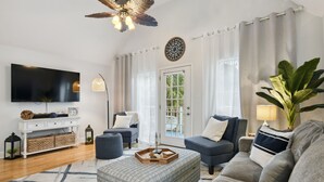 A modern living room with a flat-screen TV, a ceiling fan, and a large plant. - Beach Villa with Private Pool - Walk to beach and Island View Casino (Gulfport)