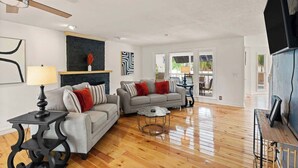 A spacious living room with a grey sofa, a round coffee table, and a ceiling fan. - Poolside Oasis - Ask about snowbird specials! (Brunswick)