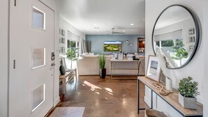 A modern, well-lit hallway with a large mirror, a view of a golf course, and a cozy seating area with a sofa and coffee table. - Casa Bonita with Private Pool / 4B/2B sleeps 8 in Old Town Scottsdale (Scottsdale)