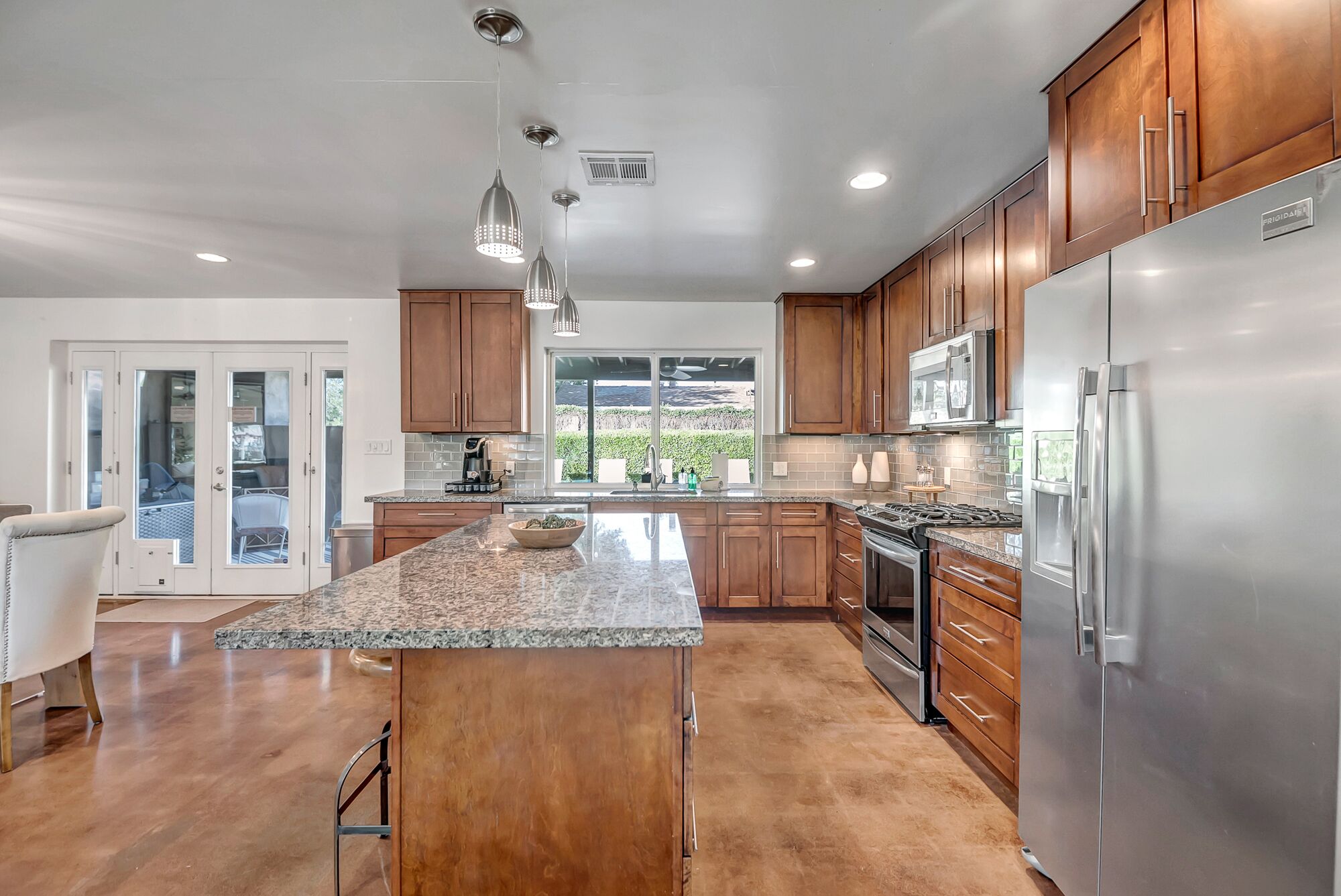 A modern kitchen with wooden cabinets, stainless steel appliances, and a large island.