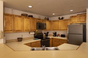 Kitchen features a central island, stainless steel appliances, and a sink with a faucet.