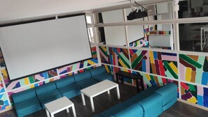 A room with a large white projection screen, a blue sofa, a white table, and a colorful abstract wall design. - 25-person apartment 10 minutes from Avignon, Bagnols sur Cèze, Marcoule, (Roquemaure)
