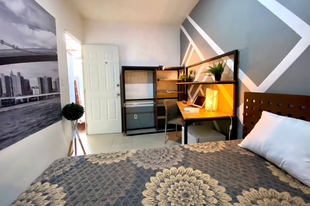 Un dormitorio con cama, un escritorio con silla, un armario y una puerta.