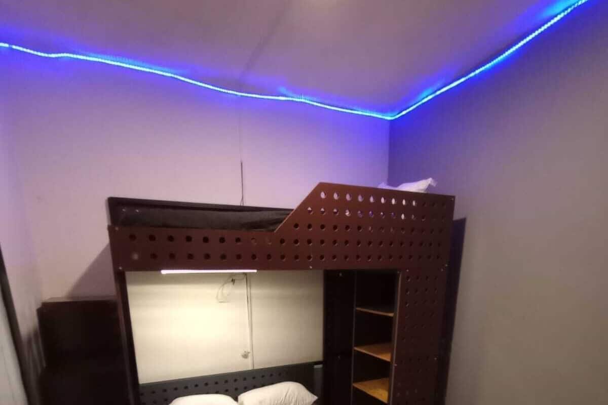 Una cama litera con cabecera, un estante pequeño y un colchón.